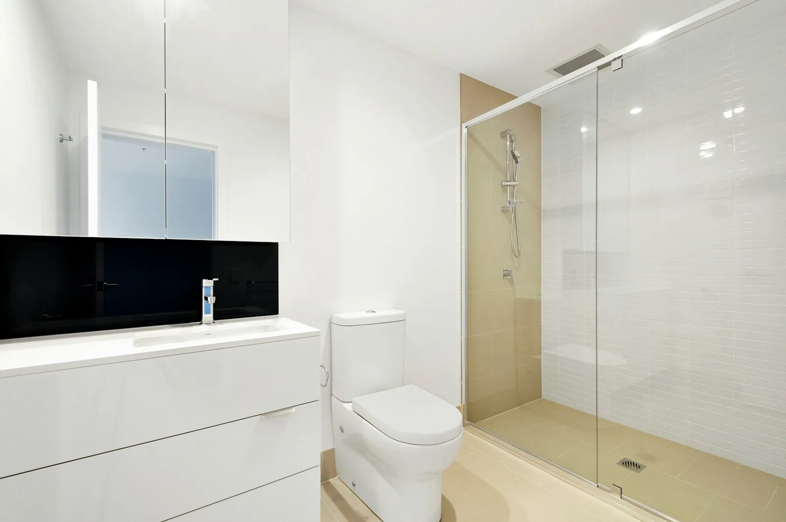 A newly fitted white bathroom with a glass shower enclosure