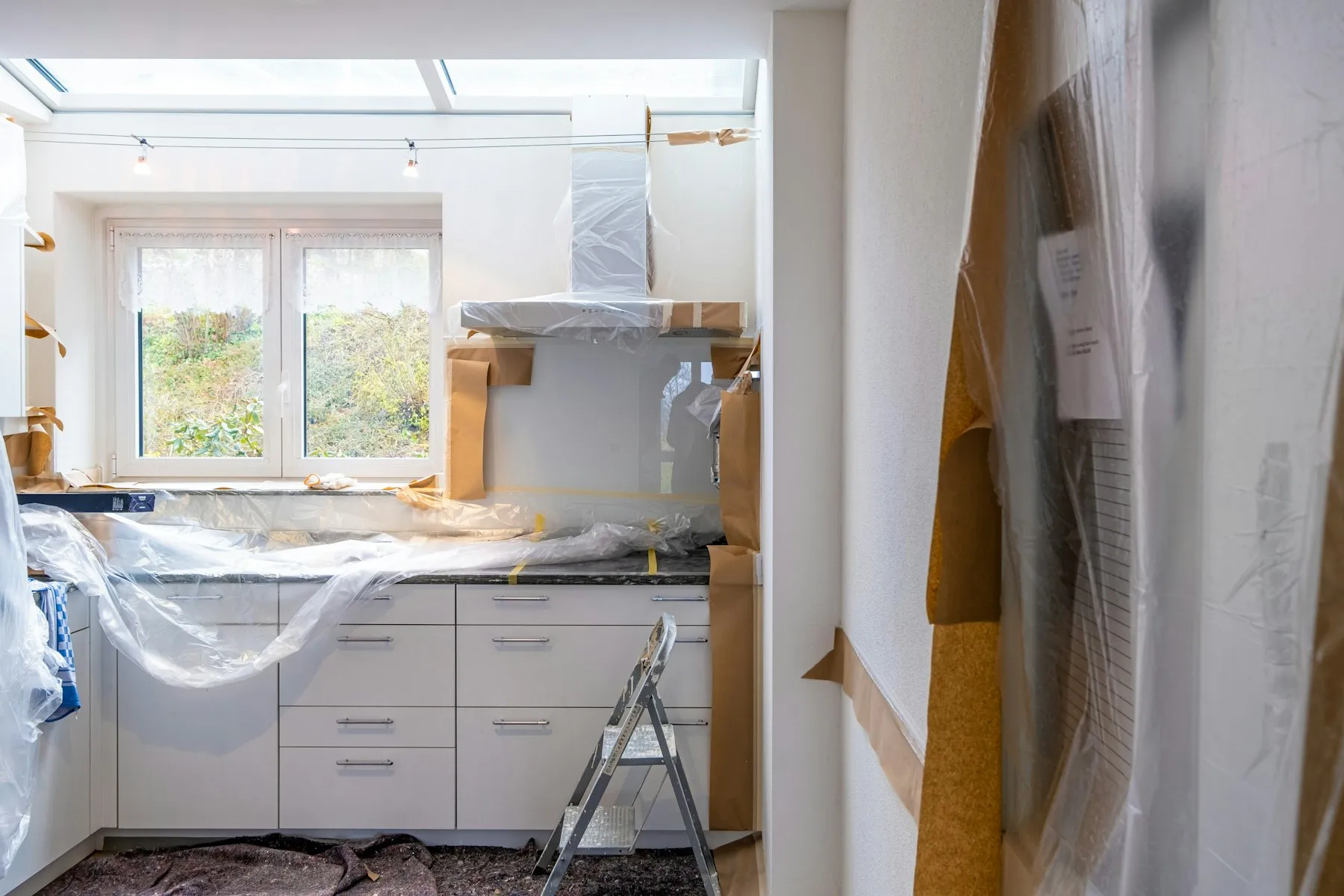A kitchen mid-renovation with units covered by dust sheets