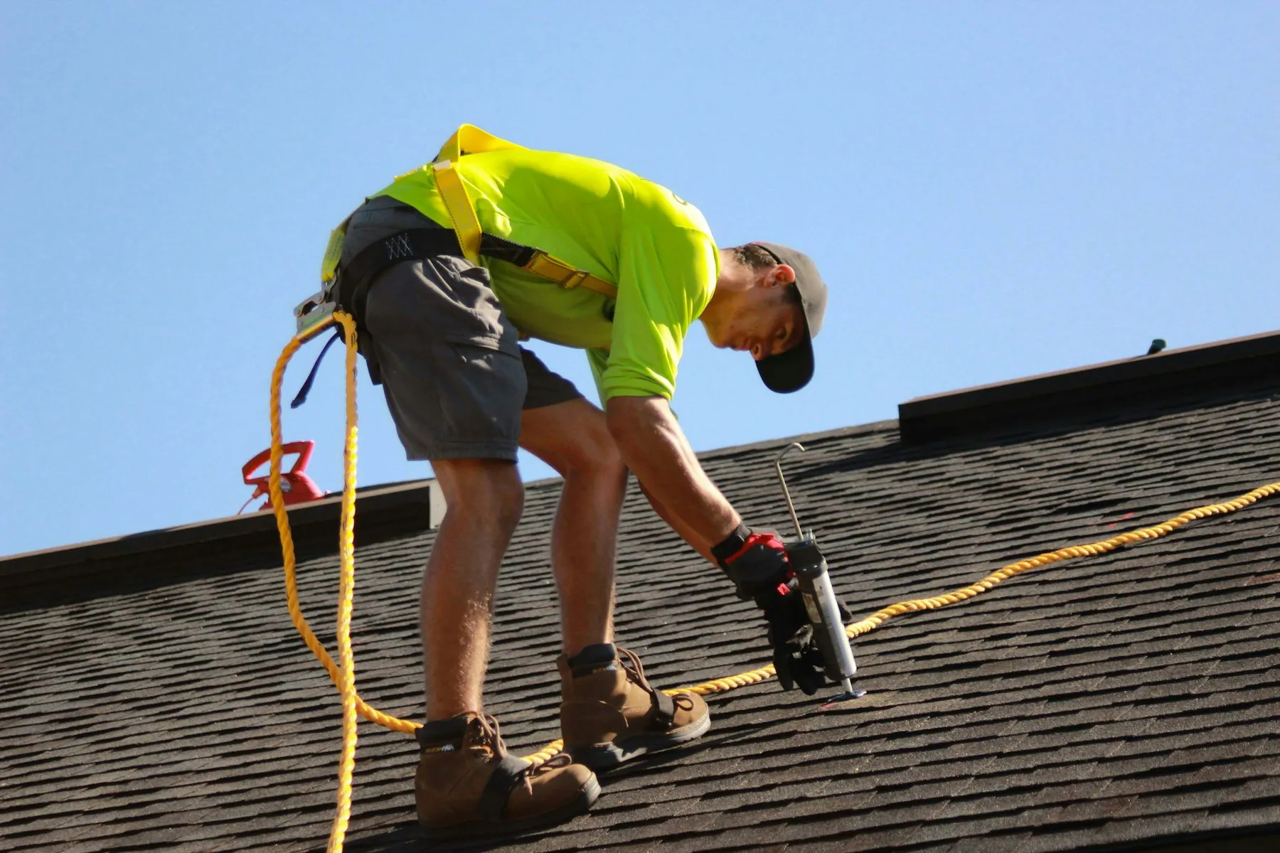 A roofer in high-visibility clothing working on a tiled roof