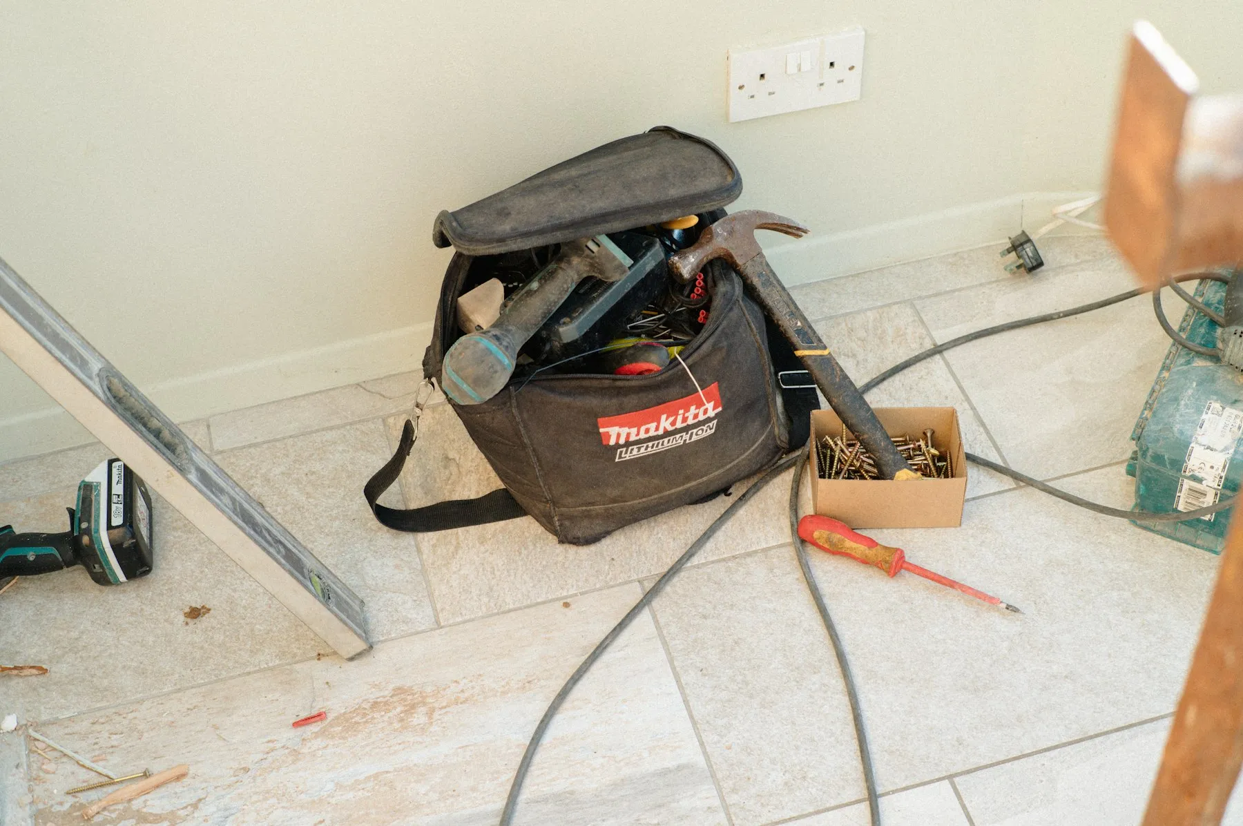 A tool bag and hand tools set down in a room during repairs